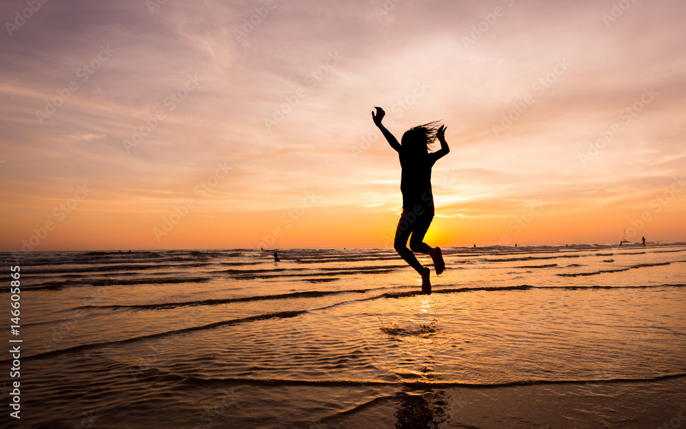 silhouette happiness man jump  during sunset or sunrise  while on holiday at the beach.