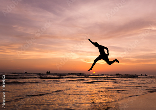 silhouette happiness man jump  during sunset or sunrise  while on holiday at the beach.