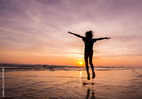 silhouette happiness man jump  during sunset or sunrise  while on holiday at the beach. © sanee
