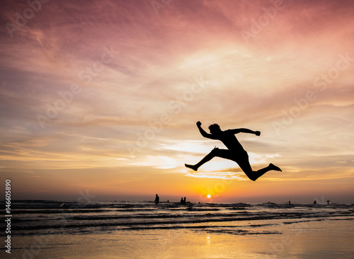 silhouette happiness man jump during sunset or sunrise while on holiday at the beach.