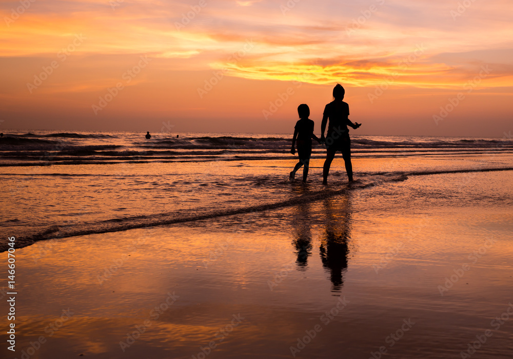 silhouette of mother and child  walking on the tropical beach  sunset background