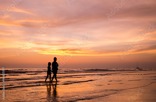 silhouette of mother and child  walking on the tropical beach  sunset background