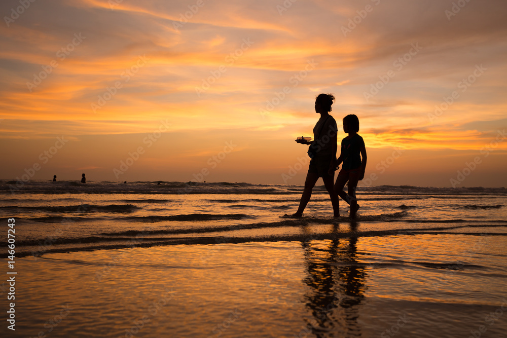 silhouette of mother and child  walking on the tropical beach  sunset background