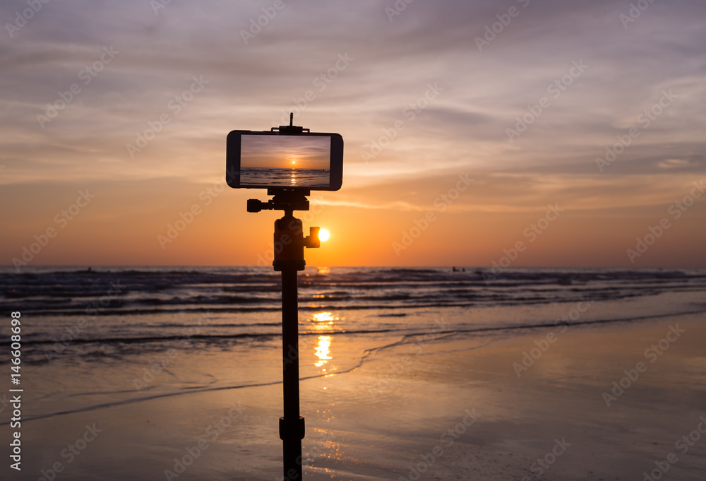 Obraz premium mobile phone shooting photo and time-lapse beautiful color sunset sky at sea