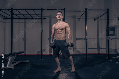 one young man, bodybuilder posing, holding dumbbells