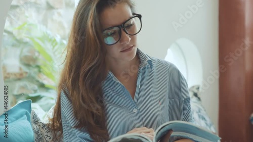Young woman reading magazine on the sofa in hotel.