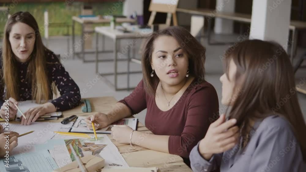 Young creative team working on architectural project. Group of mixed race people sitting at table and discussing. Young creative team working on architectural project. Group of mixed race people sitting at table and discussing.