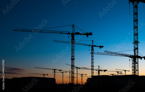 many construction cranes on sunset sky , crane silhouette skyline photo