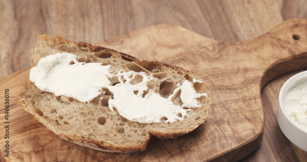 spreading ricotta cheese on fresh rustic bread, 4k photo spreading ricotta cheese on fresh rustic bread, 4k photo