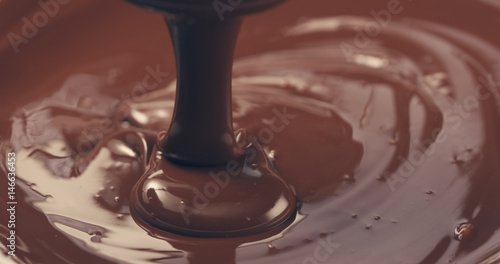 premium dark melted chocolate being poured from spoon closeup toned  4k photo