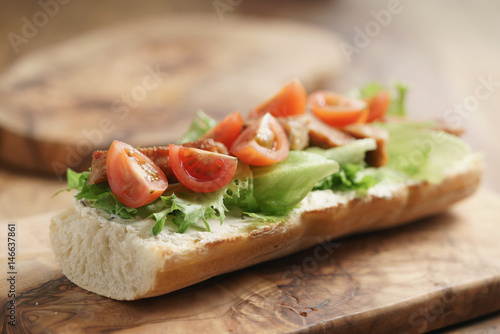 open sandwich with fried pork, salat and tomatoes on kitchen table, shallow focus