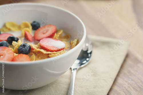 healthy breakfast with corn flakes and berries in white bowl, slightly toned photo