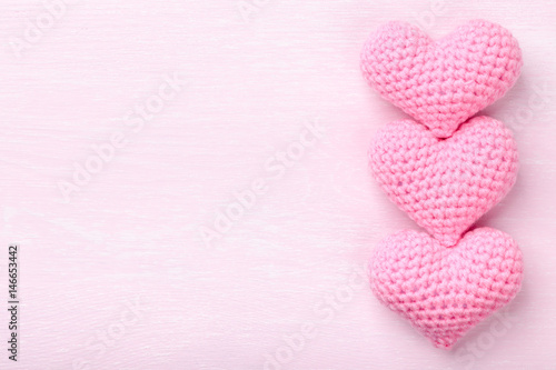 Crochet pink hearts on pink wooden background