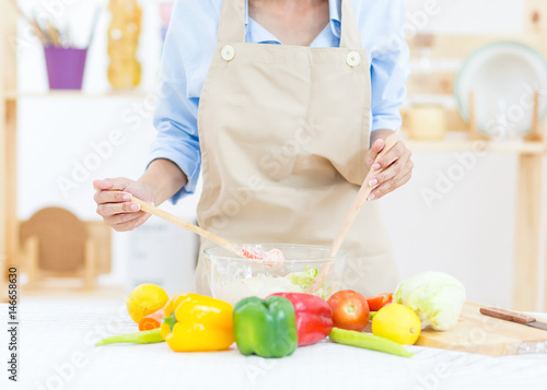 Close up of Asian girl  garnishing salads in the kitchen with others garnishing to the bowl