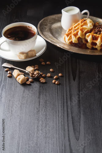Homemade belgian waffles, white ceramic cup of coffee, milk, tea