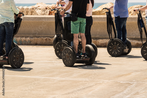A group of people are riding on electric scooter with a sea view photo
