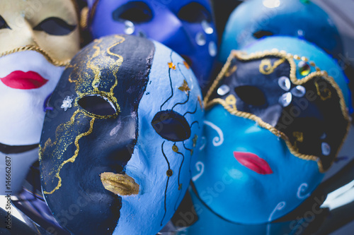 Closeup of beautiful masks made in the venetian style with acrylic paint and decoration, on the silver tray and wooden table