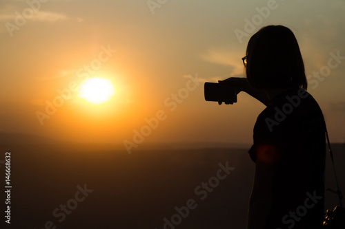 Girl takes a picture on the phone on a coal mine during the sunset
