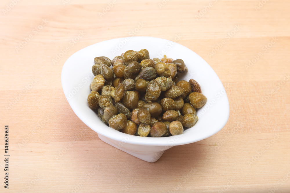 bowl with fresh capers on wooden table bowl with fresh capers on wooden table