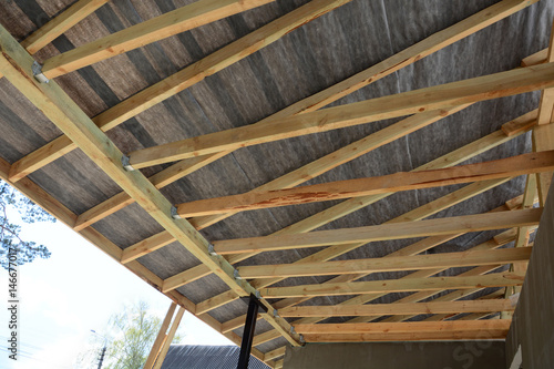 Wooden roof construction. house building. Installation of wooden beams at construction the roof truss system of the house. Installing the vapor barrier on the roof