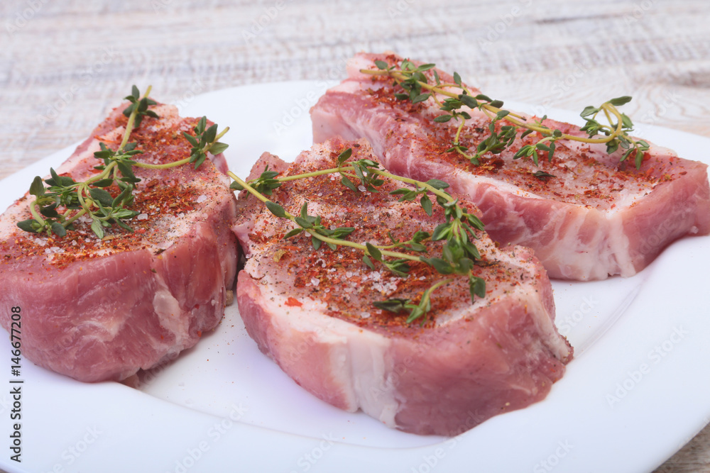 Raw pork chops, spices and rosemary on cutting board. Ready for cooking.