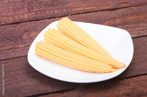 Mini Corn cob preserved on plate on wooden board.