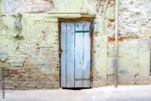 retro wooden door on a cracked concrete vintage brick wall background 