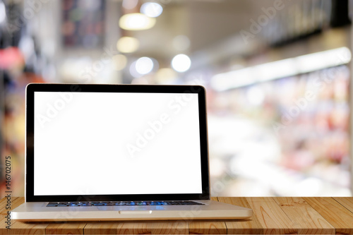 Mock up of blank laptop on the desk. Personal laptop computer on wood table in supermarket background.