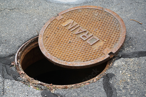 close up on opened rustic manhole cover on the street photo