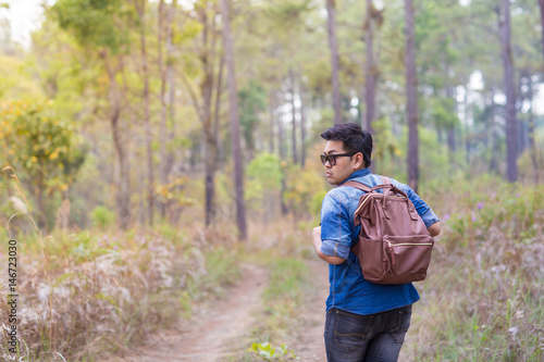 A male traveller with his sunglasses and backpack in the pine forest, Thailand