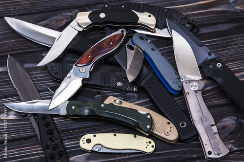 Folding knives on a wooden background photo