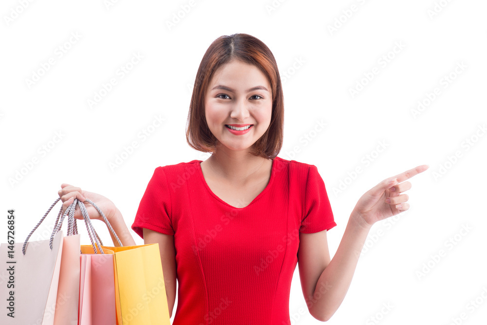 Shopping woman smiling joyful and happy holding shopping bags pointing. Asian female shopper isolated on white. Shopping woman smiling joyful and happy holding shopping bags pointing. Asian female shopper isolated on white.