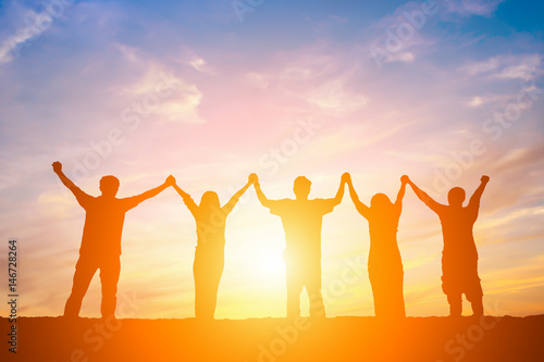 Silhouette of happy business team making high hands in sunset sky background for business teamwork concept.
