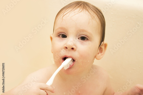 cute little boy cleans his teeth in a bath ,and plays with a toothbrush