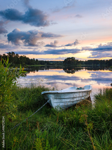 Boot liegt an stillem See im Sonnenuntergang