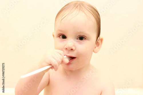 cute little boy cleans his teeth in a bath ,and plays with a toothbrush