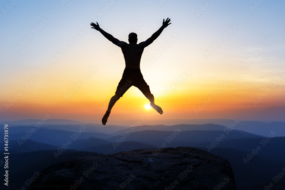 Happy man jumping for joy on the peak of the mountain, cliff at sunset. Success, winner, happiness Happy man jumping for joy on the peak of the mountain, cliff at sunset. Success, winner, happiness