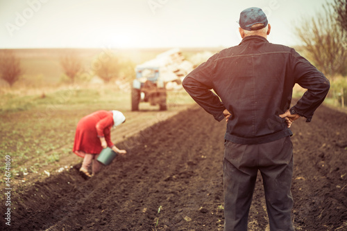 farmer looking at workers on spring farm land