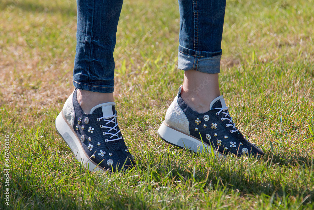 The girl is walking on the grass in sneakers