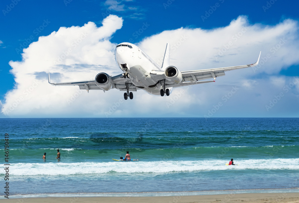 Passenger plane flies over the beach with people on the ocean coast Passenger plane flies over the beach with people on the ocean coast