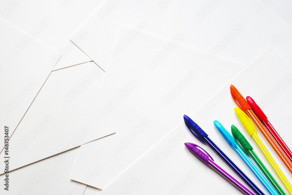 Bright colored pens on sheets of white paper Bright colored pens on sheets of white paper