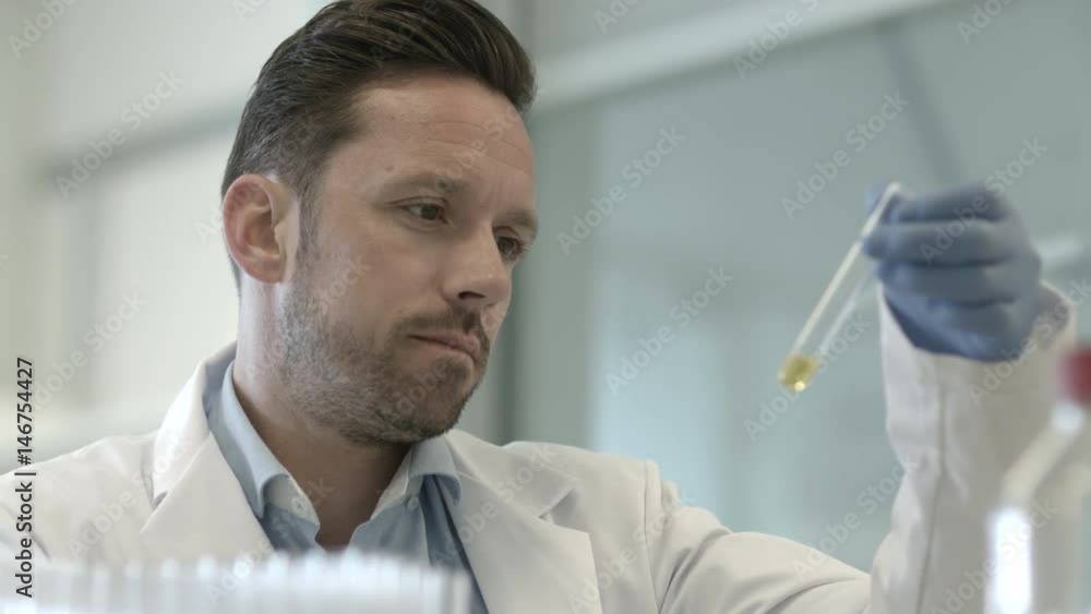 Male scientist looking at test tube in a laboratory Male scientist looking at test tube in a laboratory