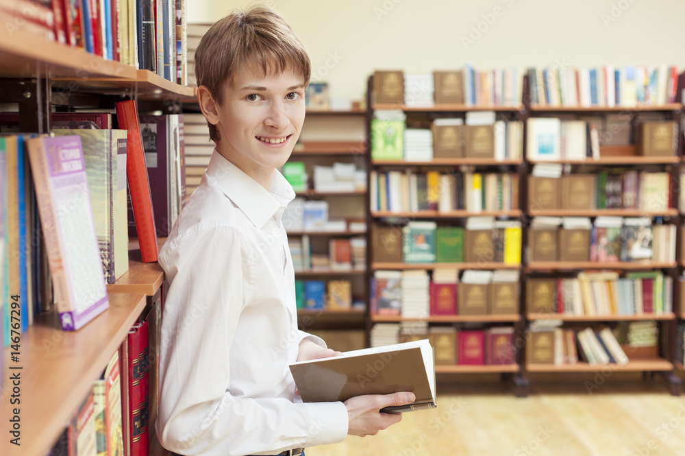 Teenager in a library with a book Teenager in a library with a book