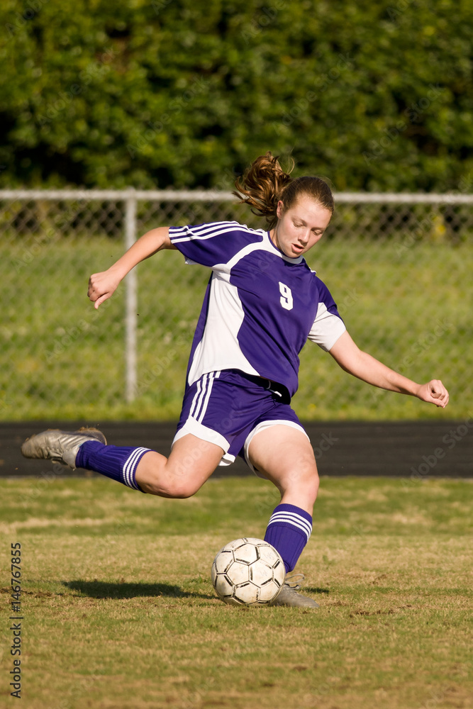 Female soccer player kicking the ball for a shot on goal