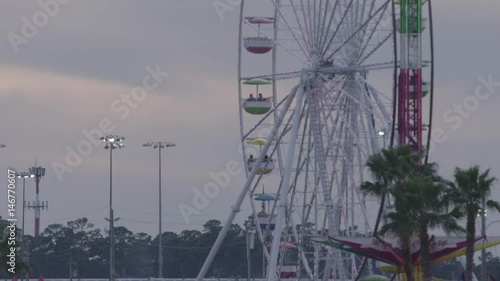 Slow motion shot of observation wheel and cleer blue sky in amusement park. Entertainment industry concept. Leisure activities, sunny summer day. photo