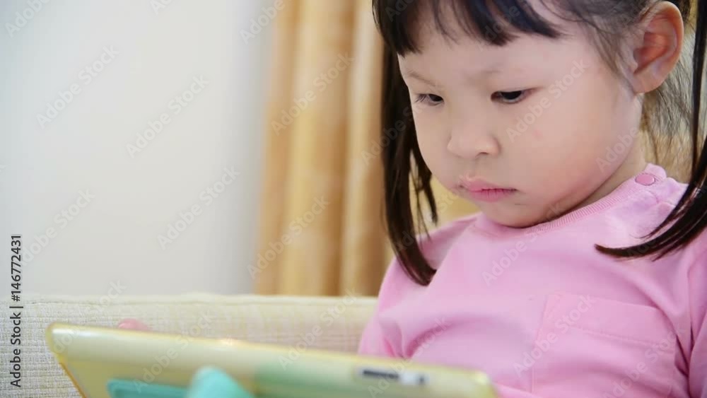Little Asian girl play tablet computer games at home
Little Asian girl play tablet computer games at home