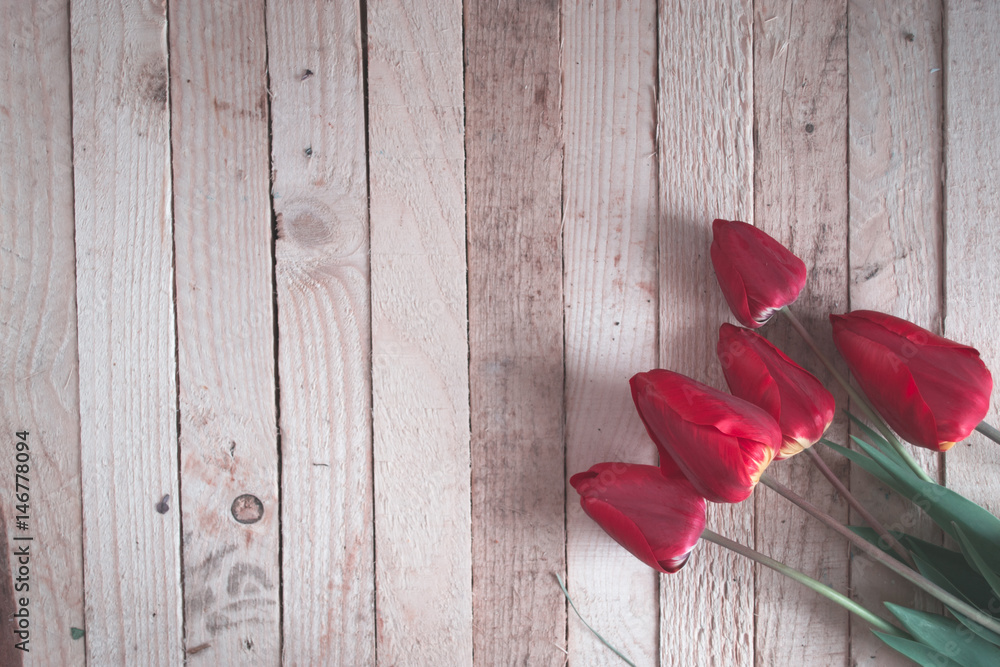 Red tulips on wooden boards.