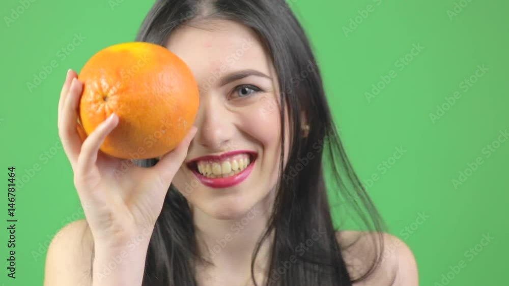 Young woman with orange, woman playing with orange and smiling Young woman with orange, woman playing with orange and smiling