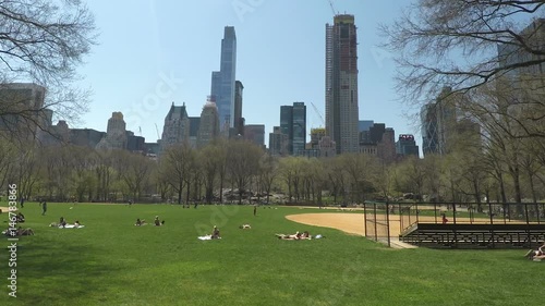 New York City, USA Central Park crowd relaxing on grass.
People recreating in Central Park at the center of Manhattan on a sunny day with a view to New York skyscrapers.
