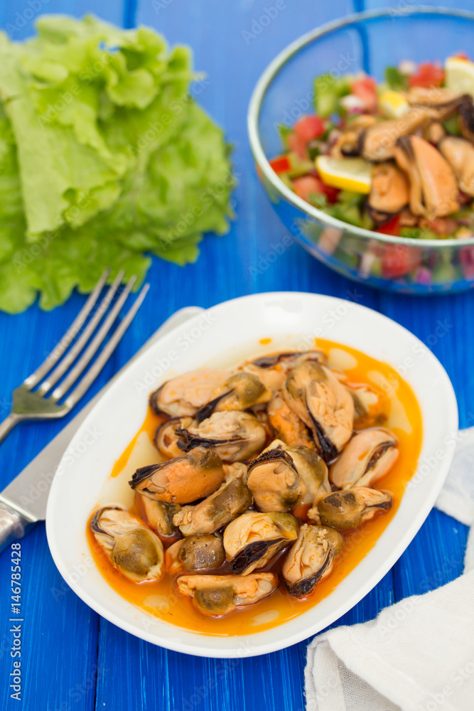 mussels in sauce on white dish on brown wooden background mussels in sauce on white dish on brown wooden background